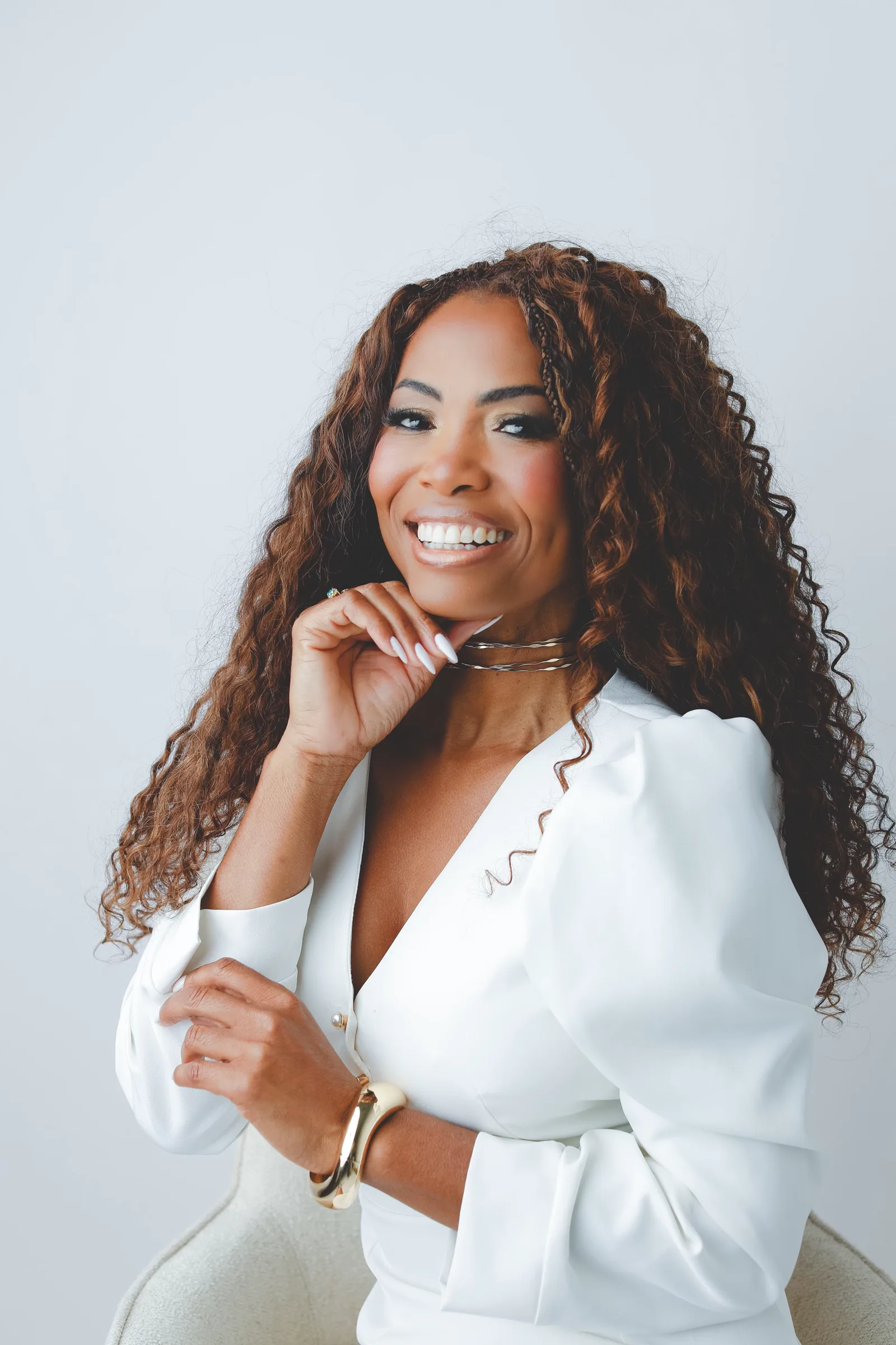 Regiane Lirio no estúdio, sorrindo de vestido branco